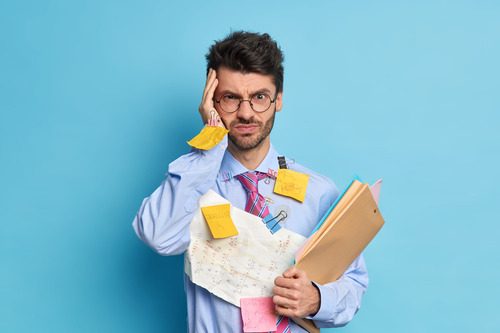 Intense serious unshaven male employee has headache because long work on project with deadline