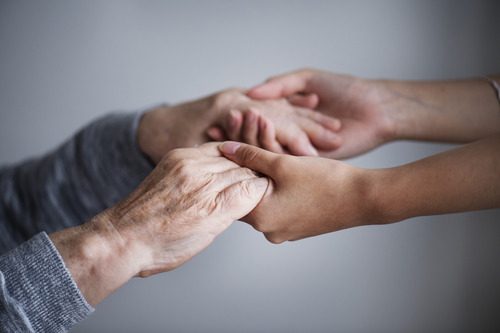 Support worker holding elderly hands