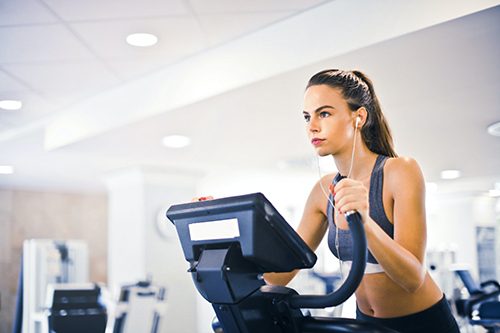 Young female athlete training alone on treadmill in modern gym