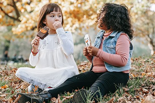 Two girls enjoy a Halloween treat on a warm fall day