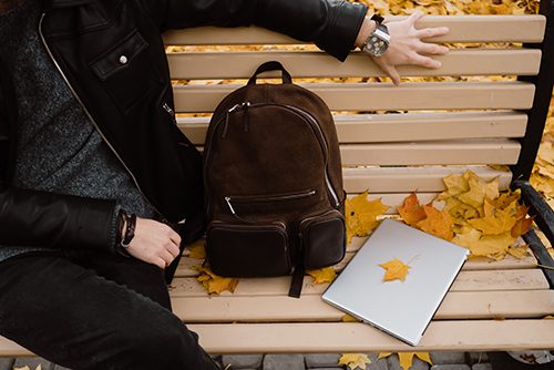 Sitting on a park bench on a fall day prepped for online classes.