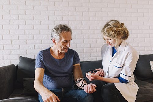 A female Health Care Aide checking an elder patient's blood pressure