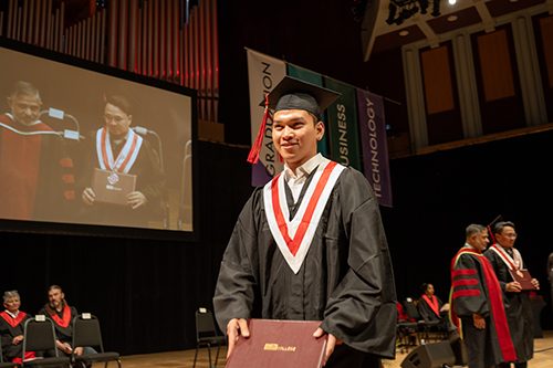 A proud graduate walking the stage after receiving his hard-earned diploma