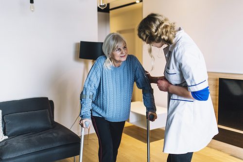 A PSW assists a patient recovering from surgery as she practices using crutches