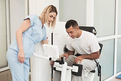 A PSW assists her client with his physiotherapy