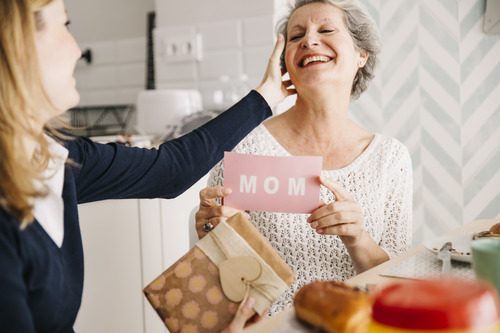 Daughter while giving a mothers day package to her mother 