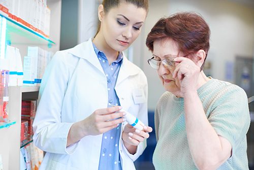 A compassionate pharmacy assistant explains the dosage and frequency of a medication to an elderly customer