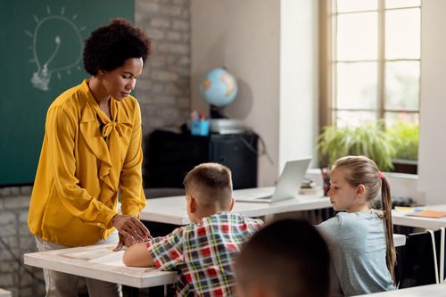 Female education assistant with two kids in class boy and girl