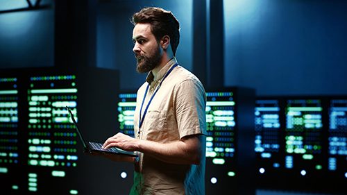 A network administrator configuring network settings on his laptop in a large server room