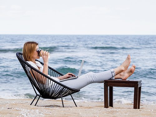 An online career college student logs into her class from the beach