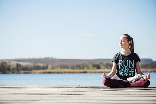 A young career college student meditates on the pier