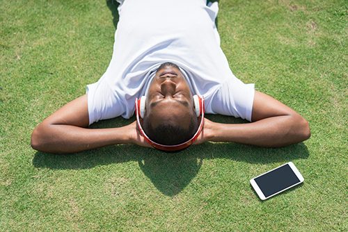 A hard working student taking a break on the grass with his favorite music