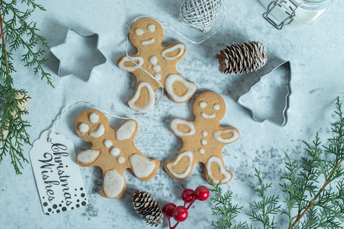 3 Gingerbreadmen are being decorated by a family as a part of their family decoration