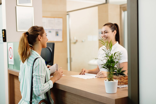 A medical receptions checks in a young woman at a doctor's ofice