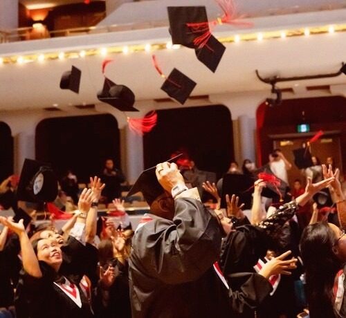 Graduates of the ABM College's Fall Graduation toss their caps