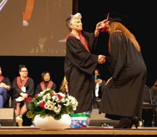 Kathy DuGray moves the tassel on a graduate's cap.