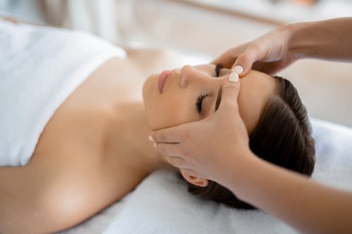 Girl receiving a facial massage to relieve stress at a beauty salon